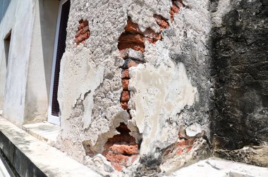 Beton bir binanın eski çatlak duvarı. Kırmızı tuğla duvarın bir kısmı Tayland 'da terk edilmiş..