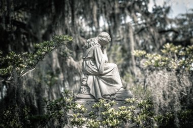 Güney Carolina 'da bir mezarlıkta İspanyol yosunlarıyla ağaçların altında bir melek heykeli.