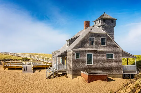 Blue sky and dunes with grass in front of the life saving station building in Provincetown