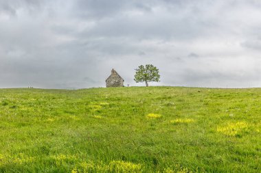 Auvergne 'deki tepede terk edilmiş eski taş ev, gökyüzü ve kötü hava.