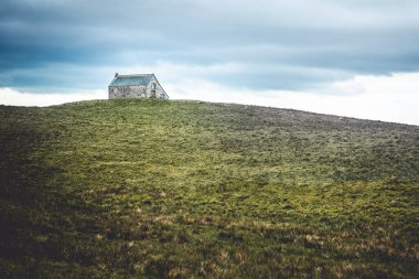 Karanlık bir günde Auvergne 'de bir tepede eski bir taş ev.