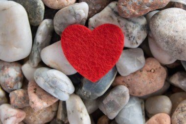 Aşk işareti romantik arka plan. Nehir kenarındaki diğer taşların üzerinde kırmızı parlak bir kalp var..