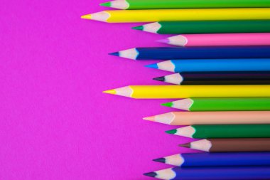 Açık pembe arka planda çok renkli kalemler var. Kapatın. Tasarım konsepti. Metin için boşluk.