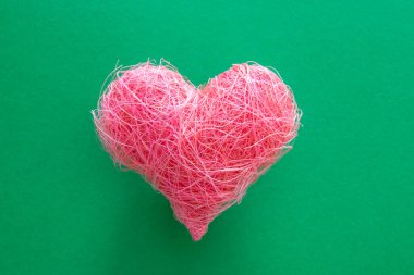 Yeşil arka planda pembe kumaştan bir kalp. Sevgililer Günü ve romantik aşk kavramı.