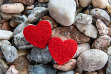 Nehir kenarındaki diğer taşlarda iki güzel kırmızı kumaş kalp. Romantik arkaplan.