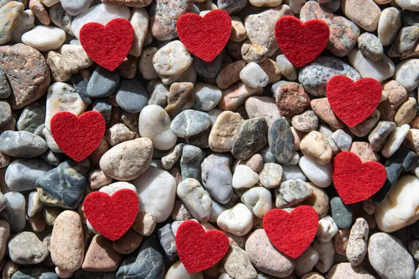 Kırmızı parlak kumaş kalpler nehrin yakınındaki taşların üzerinde.