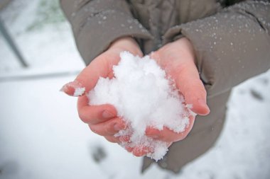 Küçük bir çocuk kışın karı elinde tutuyor. Romantik arkaplan.