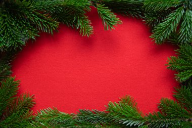 Kırmızı, parlak bir Noel geçmişi. Dokulu kumaş zemininde yeşil dalın kış çerçevesi. 