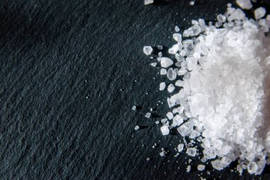 Yemeği pişirmek için tuz kristalleri. Siyah doğal bir arkaplanda deniz tuzu yığını. 