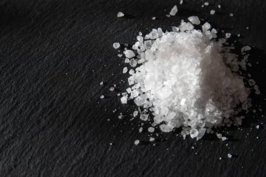 Yemeği pişirmek için tuz kristalleri. Siyah doğal bir arkaplanda deniz tuzu yığını. 