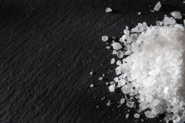 Yemeği pişirmek için tuz kristalleri. Siyah doğal bir arkaplanda deniz tuzu yığını. 