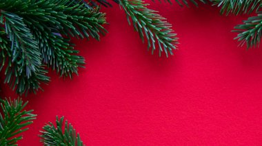 Kırmızı, parlak bir Noel geçmişi. Yeşil dalın kış çerçevesi ve kumaş arka planında iğne. Uzayı kopyala Üst görünüm. 