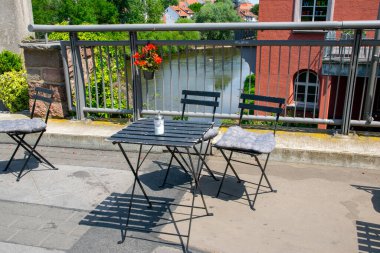 Cafe açık havada. Nehir kenarında, Almanya 'da yaz güneşinin altında sandalyeler ve masalar. Yaz kafesi veya restoranı için mobilya dizaynı.