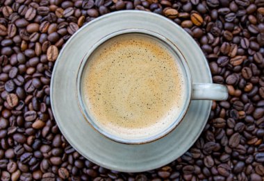 Yeşil kahve fincanı ve kavrulmuş kahve çekirdekleri. Üst görünüm.