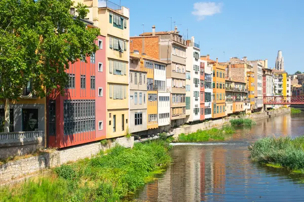 Tarihi evleri olan güzel bir cadde, küçük nehrin yakınındaki eski kasabanın merkezinde pencereler. İspanya, Girona.