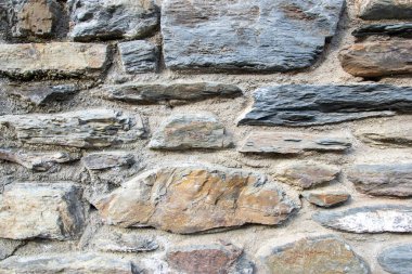 Eski binanın gri yapısal taş duvarı eski siyah tuğlalardan oluşuyor. Doğa arkaplanı.