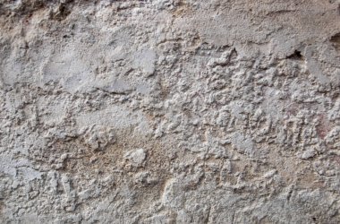 Eski binanın gri yapısal duvarı eski yapısal alçıdan oluşuyor..