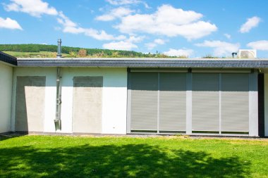 Yenilenmiş yeni bir ev, güneşli bir gökyüzünde bahçe ve ısıtma borusu, rulo. Yazın inşa ediliyor..