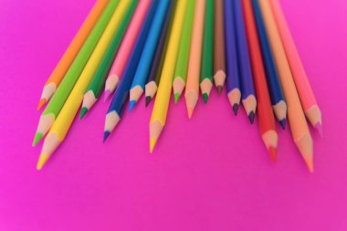 Pembe arka planda çok renkli kalemler var. Kapatın. Tasarım konsepti. Metin için boşluk. 