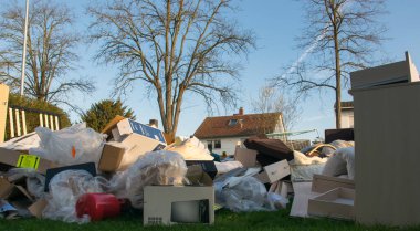 Ev yakınlarındaki bir şehirde çok fazla atık var. Eski ahşap mobilyaları, oyuncakları, kutuları, sokakta plastik torbaları ve Almanya 'da bahar güneşli çöplük gününde yeşil çimenleri olan büyük bir çöp.. 