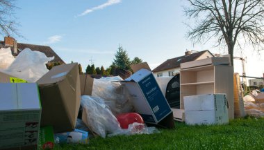 Ev yakınlarındaki bir şehirde çok fazla atık var. Eski ahşap mobilyaları, oyuncakları, kutuları, sokakta plastik torbaları ve Almanya 'da bahar güneşli çöplük gününde yeşil çimenleri olan büyük bir çöp.. 