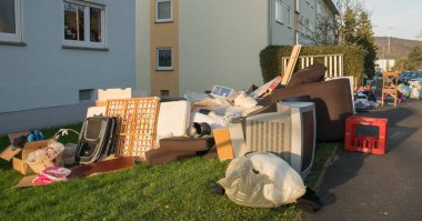 Evin yakınındaki bir şehirde israf. Eski ahşap mobilyaları, oyuncakları, kutuları, sokakta plastik torbaları ve Almanya 'da bahar güneşli çöplük gününde yeşil çimenleri olan büyük bir çöp.. 