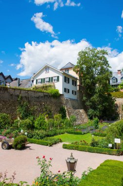 Ağaçları olan büyük, güzel bir bahçe; çiçekler ve tam bahar mevsimi çiçekleri. Bahçede bir sürü ev var..
