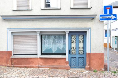 Cam pencereli eski mavi kapı gri bir eve açılıyor. Almanya 'da evleri olan ve şarkı söyleyen bir sokak..