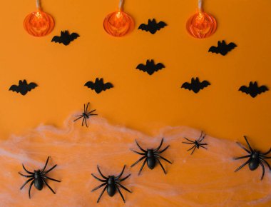 Cadılar Bayramı süslemeleri, balkabakları, yarasalar, ağ, turuncu arka planda böcekler. Parti tebrik kartı. Üst görünüm.