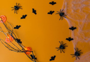 Cadılar Bayramı süslemeleri, balkabakları, yarasalar, ağ, turuncu arka planda böcekler. Fotokopi alanı olan Cadılar Bayramı partisi tebrik kartı. Düz yatış, üst görünüm.