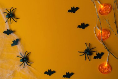 Cadılar Bayramı süslemeleri, balkabakları, yarasalar, ağ, turuncu arka planda böcekler. Kopya alanı olan parti tebrik kartı. 