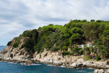 Adadaki otel, palmiye ağaçları, kafe, deniz kıyısındaki insanlar. İspanya 'daki Sealine' in panoramik hava görüntüsü.