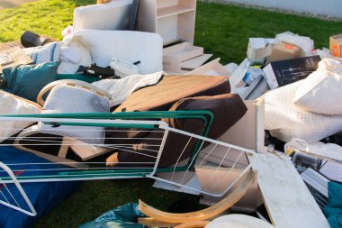 Ev yakınlarındaki bir şehirde çok fazla atık var. Eski ahşap mobilyaları, oyuncakları, kutuları, sokakta plastik torbaları ve Almanya 'da bahar güneşli çöplük gününde yeşil çimenleri olan büyük bir çöp.. 