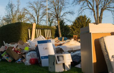 Eski ahşap mobilyaları, oyuncakları, kutuları, sokakta plastik torbaları ve Almanya 'da bahar güneşli çöp atma gününde yeşil çimenleri olan büyük bir çöp. Evin yakınındaki bir şehirde çok fazla atık var.. 