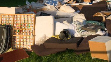Eski ahşap mobilyaları, oyuncakları, kutuları, sokakta plastik torbaları ve Almanya 'da bahar güneşli çöp atma gününde yeşil çimenleri olan büyük bir çöp. Evin yakınındaki bir şehirde israf.. 