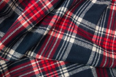 Kış kaşmir atkısı. Mavi, beyaz, kırmızı kafes dokusu. Tekstil koyu renkli örgü arka plan.