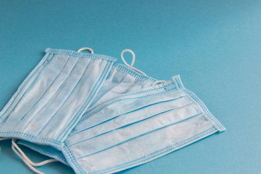 Mavi arka planda yüz için tıbbi maske. Kirliliğe ve virüs korumasına karşı antibakteriyel. Covid-19 - tüm dünyada koronavirüs enfeksiyonu. Sağlık hizmetleri.