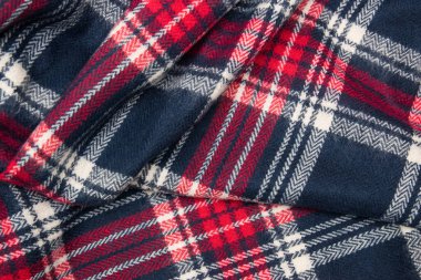 Kış kaşmir atkısı. Mavi, beyaz, kırmızı kafes dokusu. Tekstil koyu renkli örgü arka plan.