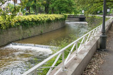 Yazlık şehirde şelale ve eski bir köprü. Doğa geçmişi. Güneşli bir günde temiz suyla şelaleler ve yeşil ağaçlarla çevrili.