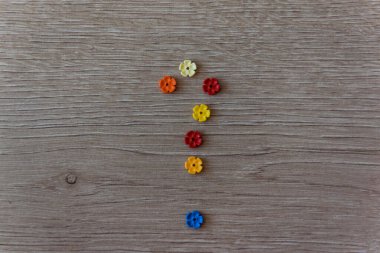 Ahşap arka planda plastik renkli çiçek legosunun soru işareti var. Karışıklık, soru veya çözüm kavramı.