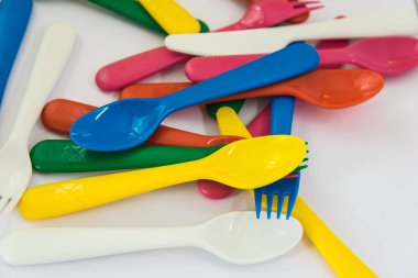 Beyaz arkaplanda çok renkli plastik kaşıklar.