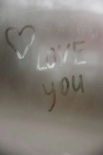 Beautiful heart symbol and love you word on the glass window with water drobs.