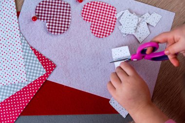 Çocuğun eli, kalpten tebrik kartı yapar. Arka planda süsleme var. Hobi konsepti. El yapımı. ÇOCUK kavramı.