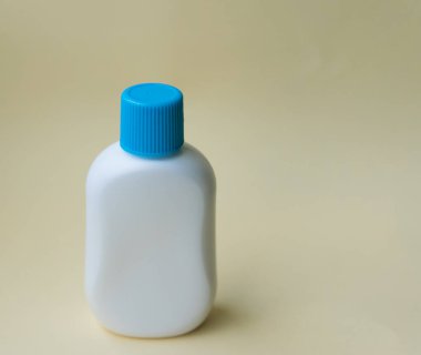 Krema için beyaz plastik şişe ya da sarı arka planda yağ. Kopyalama. Metin için boşluk.