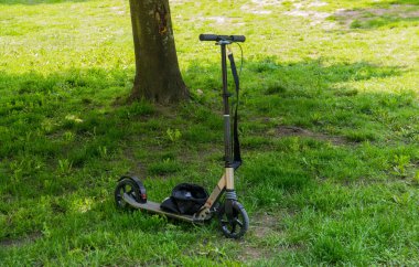 Yazın güneşli bir günde yeşil çimlerin üzerinde elektrikli scooter 'ı kapat. Sağlıklı yaşam tarzı.