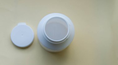 Sarı arka plandaki haplar için beyaz bir şişe aç. Çiftlik konsepti. Düz yatıyordu. Uzayı kopyala Metin için boşluk.