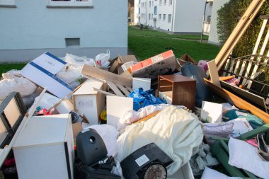 Ev yakınlarındaki bir şehirde çok fazla atık var. Eski ahşap mobilyaları, oyuncakları, kutuları, sokakta plastik torbaları ve Almanya 'nın güneşli çöplük gününde yeşil çimenleri olan büyük bir çöp.. 