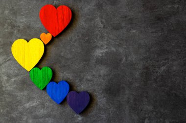 Taşın siyah zemininde gökkuşağının renkleri tahta kalpler. Lgbt bayrağı. 