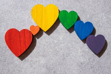 Rainbow colors wood hearts on the stone black background. Lgbt flag.  clipart