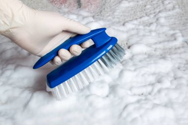 Fırçalı lastik eldiven verin. Plastik mavi fırça ve yerdeki temizlik için bolca beyaz köpük. Ev temizliği kavramı.